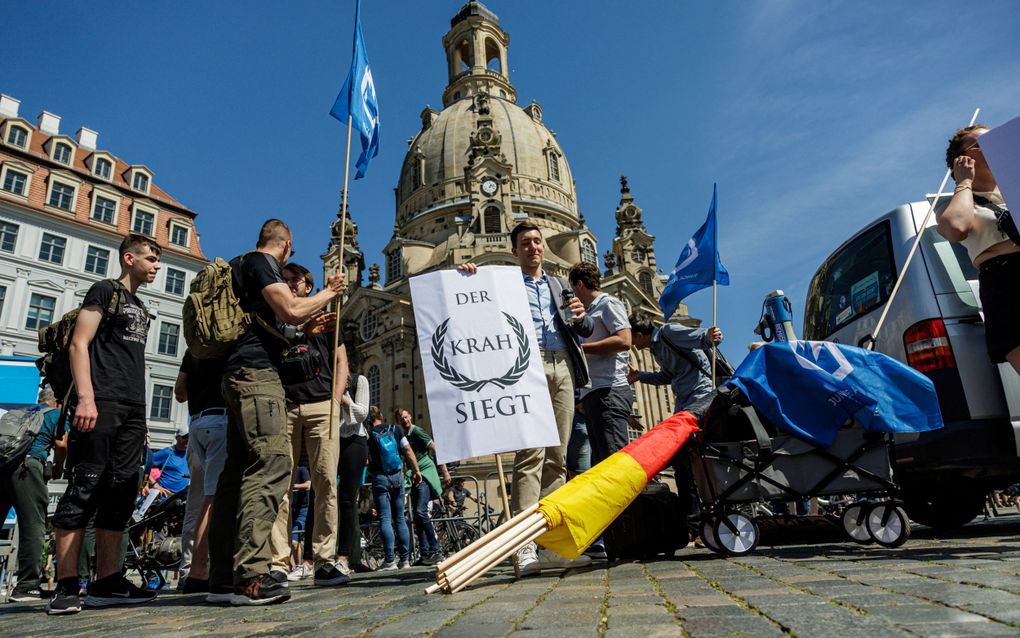 Aanhangers van de AfD houden voor de Frauenkirche in Dresden posters vast met de tekst ”Krah wint” tijdens een campagne-evenement voor de komende Europese verkiezingen. AfD-lijsttrekker Krah ligt onder vuur na verdenking van omkoping door Rusland en China. beeld AFP, Jens Schlueter 