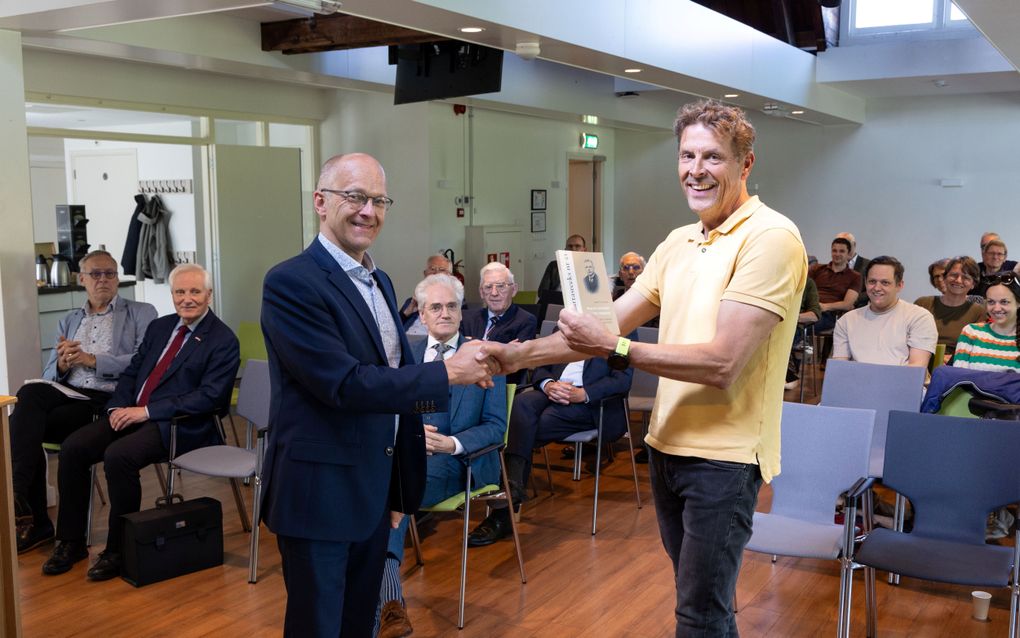 Dr. Geert van Dijk, auteur van een studie over ds. B. Telder, biedt dinsdagmiddag in het gebouw van de Theologische Universiteit Utrecht (TUU) zijn boek aan een kleinzoon van ds. Telder aan. beeld RD, Anton Dommerholt