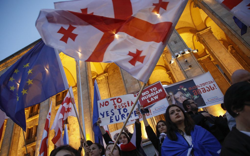 Betogers zwaaien met Georgische en Europese vlaggen tijdens een demonstratie buiten het parlementsgebouw in Tbilisi tijdens de laatste stemming over de buitenlandse-agentenwet. beeld ANP, David Mdzinarishvili