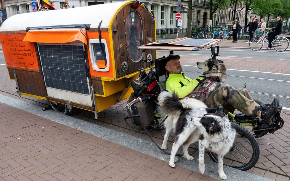 Max le Bourlingueur met zijn zelfgemaakte fietskar, op een brug over de Amsterdamse Herengracht. beeld Ronald Bakker