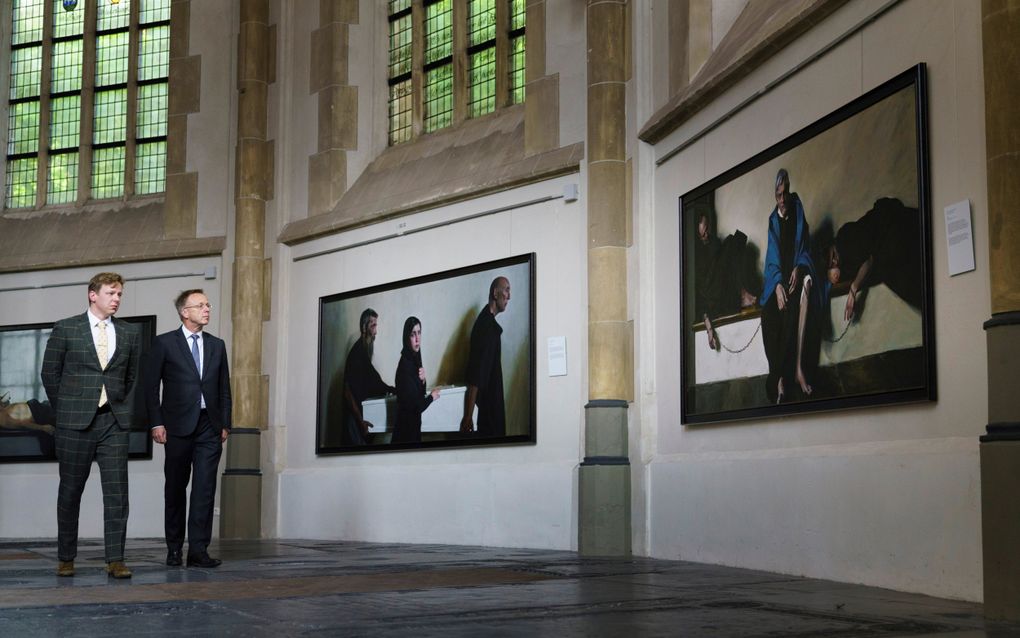 Kunstenaar Egbert Modderman (l.) en commissaris van de Koning René Paas lopen in de kooromgang van de Martinikerk in Groningen langs de schilderijen uit de reeks ”Werken van barmhartigheid”. Het laatste werk in de serie werd vrijdag onthuld. beeld Reyer Boxem