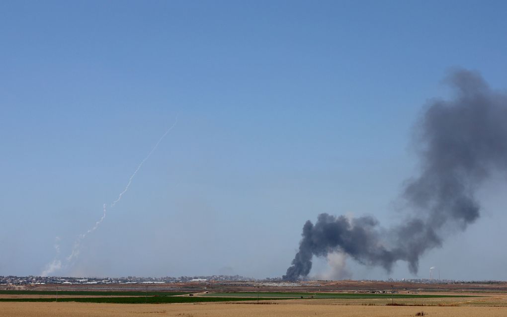 Rook stijgt op boven Jabalia, in de noordelijke Gazastrook, na een Israëlisch bombardement. Links wordt een raket afgeschoten. Hamas eist, als onderdeel van een bestand, dat Israël zich volledig terugtrekt uit Gaza. beeld EPA, Atef Safadi