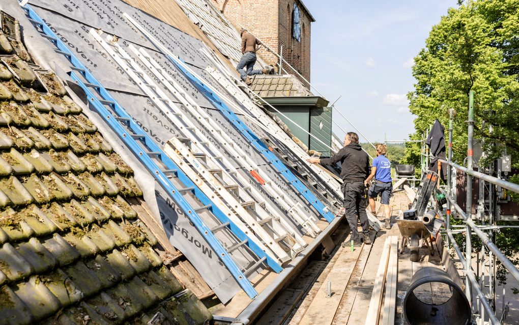 De Dorpskerk in Garderen wordt aan de noordkant voorzien van nieuwe dakpannen. Volgens kerkvoogd Gerrit van Lagen van de hersteld hervormde gemeente in de Gelderse vakantieplaats waren de oude pannen hard aan vervanging toe. „De oude dakpannen zijn zo’n zeventig, tachtig jaar oud en beginnen uit elkaar te vallen.” beeld André Dorst