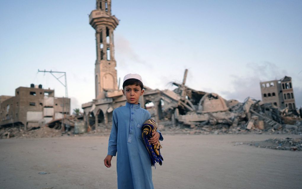 Een Palestijnse jongen poseert met zijn gebedsmatje onder de arm in het zuiden van de Gazastrook. beeld AFP, Bashar TALEB