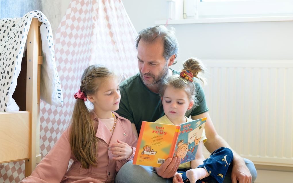 Een vader leest zijn dochters voor, thuis in hun slaapkamer. beeld ANP, Roos Koole