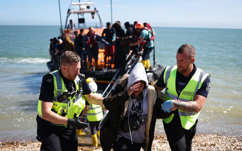 Britse agenten helpen een migrant van een schip van de Engelse kustwacht het strand op bij Dungeness in Zuidoost-Engeland. De migranten zijn zojuist op zee in het Kanaal opgepikt. beeld AFP, Henry Nicholls