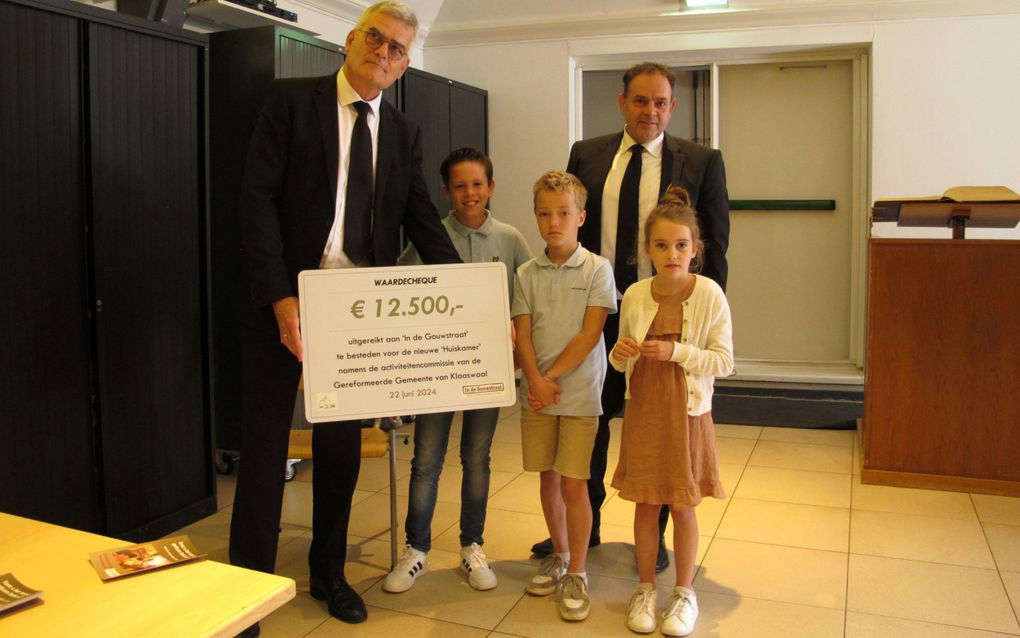 Johan de Vries (l.) met de cheque die hij van drie kinderen uit Klaaswaal kreeg. Achter hen diaken Alfred van der Slikke. beeld Rinus Zwemer