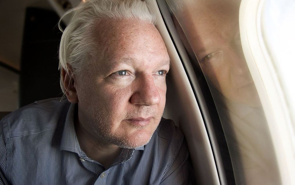  Wikileaksoprichter Julian Assange kijkt uit het raam van het vliegtuig dat hem naar het eiland Saipan brengt. beeld AFP, WikiLeaks