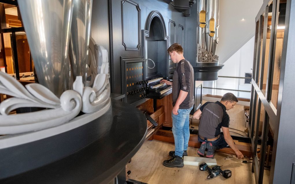 Piet Vader (l.) en Laurens Drooger van orgelmakerij Boogaard klussen aan de toekomstige werkplek van de organist in de nieuwe kerk van de gereformeerde gemeente Yerseke. In totaal zal het orgel vijftig registers tellen, verdeeld over drie klavieren en pedaal. beeld Dirk-Jan Gjeltema