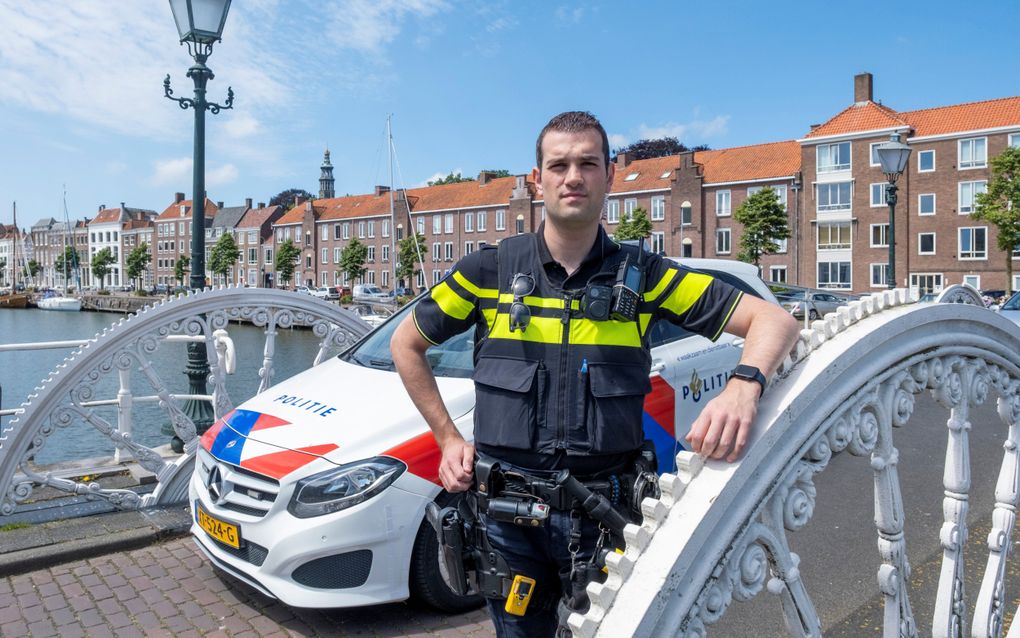 Politieagent Frank Zuidijk voor zijn dienstauto, in de Zeeuwse stad Middelburg. Om de week moet hij op zondag werken. beeld Dirk-jan Gjeltema