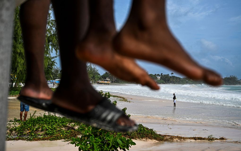 Een man loopt over het strand van Barbados nadat orkaan Beryl is weggetrokken. beeld AFP, Chandan Khanna 