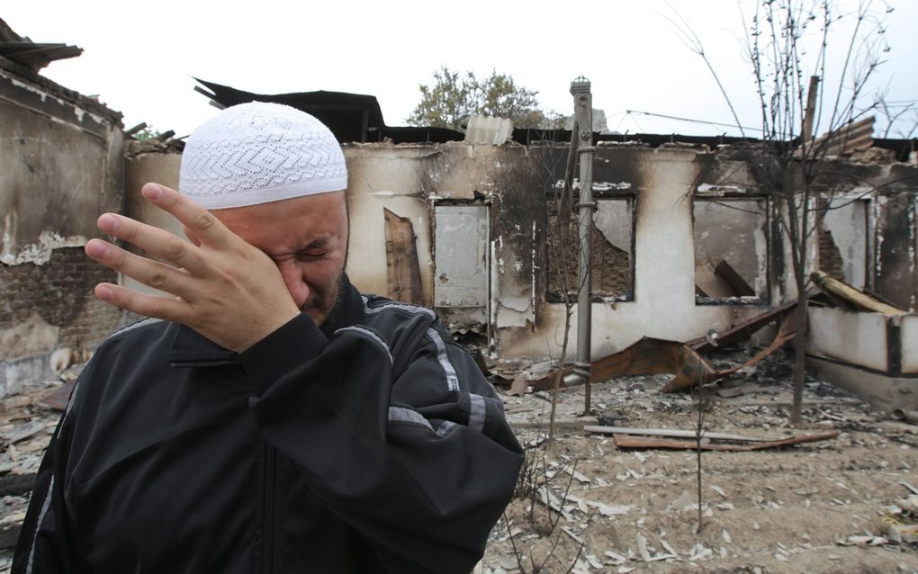 Een etnische Oezbeek treurt bij de ruïne van zijn huis, dat donderdag verwoest werd tijdens etnische onlusten in Osj in Zuid-Kirgizië. Foto EPA