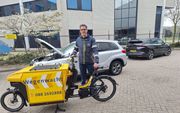 Wegenwacht Martin van Wijk met elektrische bakfiets naast een auto met pech. beeld ANWB