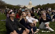 Voor het Capitool in de Amerikaanse hoofdstad Washington D.C. turen Amerikanen maandag door eclipsbrillen naar de zonsverduistering. beeld EPA, Michael Reynolds