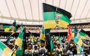 Aanhangers van het African National Congress (ANC) zwaaien met vlaggen tijdens de presentatie van het verkiezingsmanifest in een stadion in Durban op 24 februari 2024. beeld AFP, Rajesh Jantilal