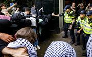 In het nauw gedreven politieagenten gebruikten pepperspray en wapenstok om pro-Palestina-activisten bij de Universiteit van Amsterdam in bedwang te houden. Actievoerders eisen dat de banden met Israëlische instellingen worden verbroken. beeld ANP, Ramon van Flymen