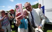 Reform UK-partijleider Nigel Farage maakt een selfie met een fan. beeld EPA, Andy Rain