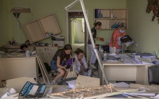 Medisch personeel ruimt het puin in een zwaar beschadigd gebouw van het Ochmatdytziekenhuis na een Russische raketaanval in de Oekraïense hoofdstad Kyiv. beeld AFP, Roman Pilipey 