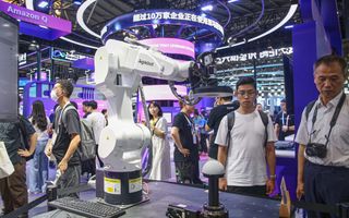 Bezoekers van de World Artificial Intelligence Conference in Shanghai bekijken een nieuw type robotarm. beeld AFP