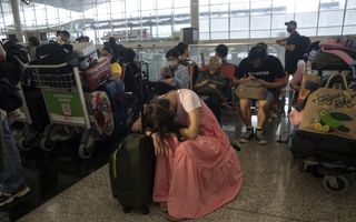 Een vermoeide reiziger laat de moed zakken op de internationale luchthaven van Hong Kong tijdens de wereldwijde technische IT-storing op vrijdag 19 juli. beeld EPA, Leung Man Hei 