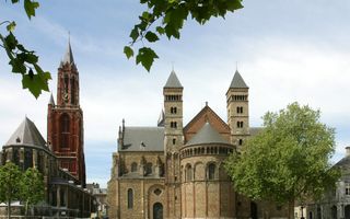 Twee oude kerken naast elkaar: een met een roodkleurige toren en een ander met twee torens. 