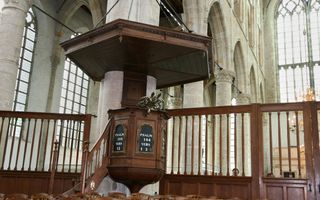 Preekstoel in een oude kerk met pilaren en hoge ramen.