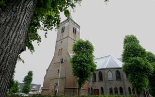 Kerk met een hoge toren, omgeven door bomen.