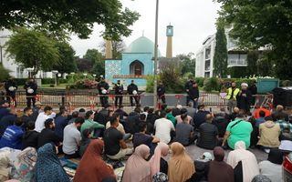 Blauwe moskee. Op voorgrond moslims. Achter hekken staan agenten.