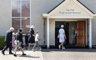 Een man, vrouwen en kinderen lopen door een kerkdeur naar binnen.