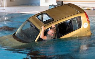Jonge man probeert te ontsnappen uit het raam van een auto die naar de bodem van een zwembad zinkt.