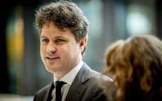 Vriendelijke man in grijs pak met zwarte stropdas.