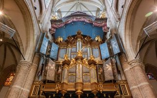 Een oud orgelfront heeft aan beide kanten beschilderde orgelluiken en hangt in de oude kerk.