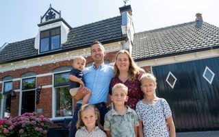Gezin voor hun huis met de naam Ora et Labora in top.
