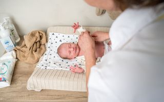 Zorgverleenster van RST verschoont een baby op een commode. 