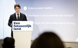 Man staat achter spreekgestoelte met daarop een slogan.