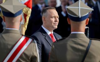 Een man in pak kijkt met een schuin oog naar een militaire garde.