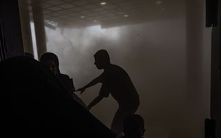 Silhouetten in een met rook en stof gevulde ruimte.