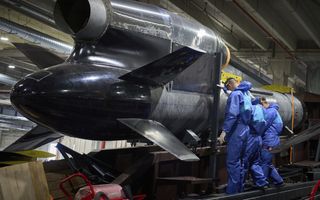 Mannen in blauwe pakken inspecteren een grote raket 