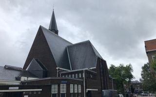 Historisch kerkgebouw met op de voorgrond geparkeerde auto’s.