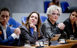 Een man en drie vrouwen zitten in het kabinetsvak van de plenaire zaal van de Tweede Kamer.