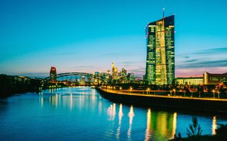 Het gebouw van de Europese Centrale Bank en de skyline van Frankfurt am Main na zonsondergang.