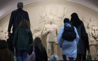 Mensen lopen voor een reliëf met mensen erop. 