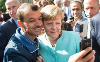 Een vrouw in een blauw jasje maakt een selfie met een man in een blauwe jas. 