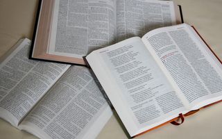 Tafel met daarop drie opengeslagen Bijbels in verschillende vertalingen.