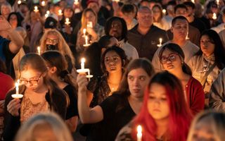 Mensen houden brandende kaarsjes omhoog tijdens bijeenkomst. 
