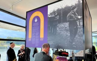 Militair in uniform bij tentoonstellingstekst.