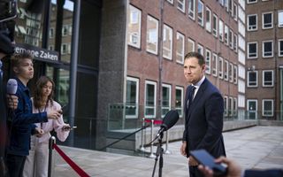 Man in pak staat tegenover journalisten.