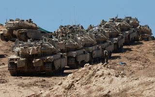 Tanks staan in een rij op zandgrond.