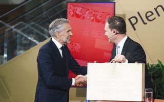 Twee mannen in pak geven elkaar de hand, de een heeft in zijn hand een koffertje.