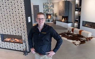 Man met bril kijkt met zijn handen in de zij naar de camera. Om hem heen zijn vier verschillende haarden te zien. 